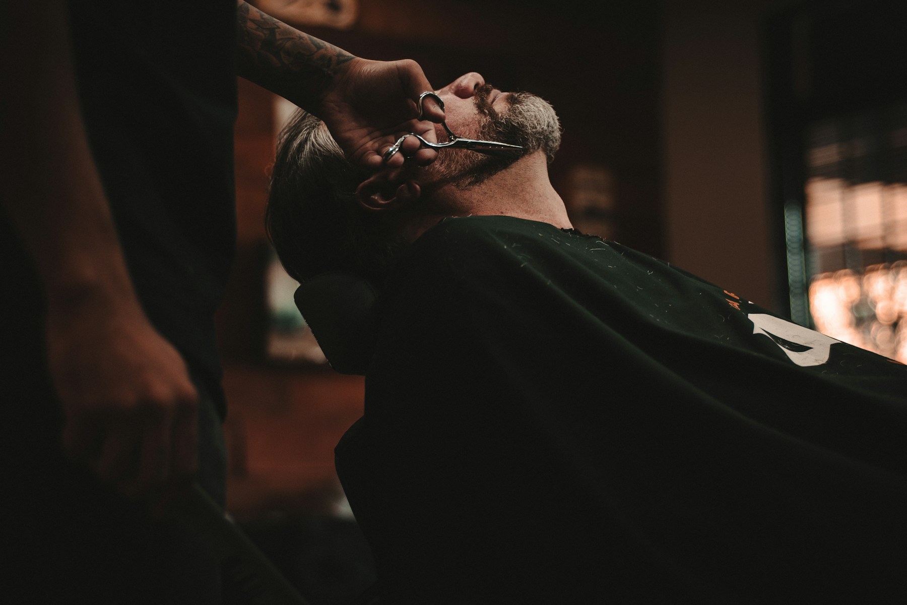 Barber carefully trimming a client's hair with scissors